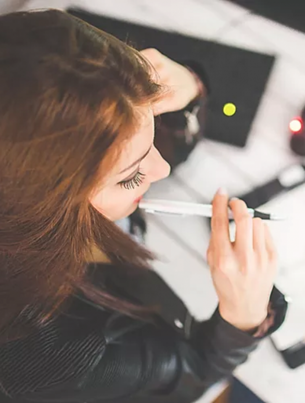 woman biting pen thinking office